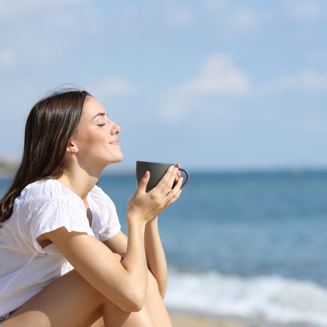 women enjoying a cup of gratitude ritual superfood blend on the beach eyes closes expressing gratitude